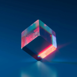 Cubo de cristal translúcido que emite destellos multicolores vibrantes contra un fondo azul sólido